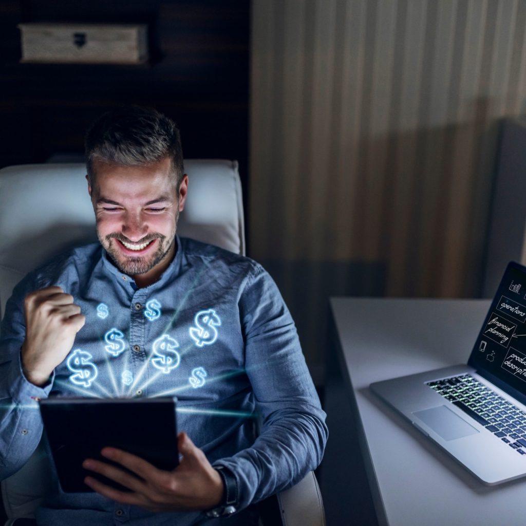 Junger Geschäftsmann mit iPad und Laptop freut sich über Automatisierung